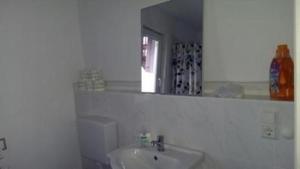 un bagno bianco con lavandino e specchio di Ferienwohnung in Vorland mit Grill und Garten a Vorland