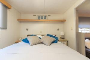 a bedroom with a large white bed with blue pillows at Mobile homes Bepo in Sveti Filip i Jakov