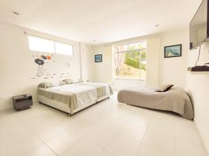 una camera da letto bianca con due letti e una finestra di Bellísima casa quinta capacidad 20 personas a Melgar Altre 16 foto