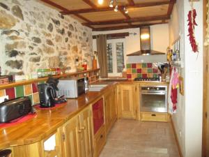 una cucina con mobili in legno e un muro in pietra di L'Olivier Chez Mamé Marthe a Vallon-Pont-dʼArc