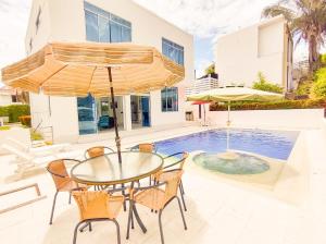 un tavolo con sedie e un ombrellone accanto alla piscina di Bellísima casa quinta capacidad 20 personas a Melgar