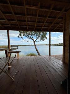 a wooden porch with a bench and a tree on a lake at COMPORTA SIDE - Lake in Setúbal