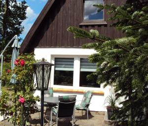 Un patio con una mesa y sillas frente a una casa. en Reetgedecktes Ferienhaus, en Ostseebad Karlshagen