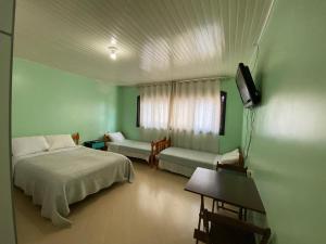 a bedroom with a bed and a couch and a television at Pousada 355 in Passo Fundo