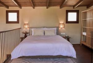 a bedroom with a large white bed with two lamps at Pappon Homestead in Pemónia