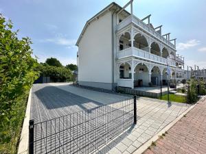 ein weißes Gebäude mit einem Zaun davor in der Unterkunft Haus Concordia 2 Möwennest in Thiessow