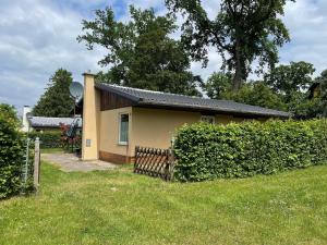 a small yellow house with a fence in a yard at Ferienhaus in Dahmen mit Großem Garten in Dahmen