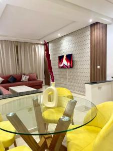 a dining room with a glass table and yellow chairs at New Luxurious apartment Agdal Rabat center in Rabat