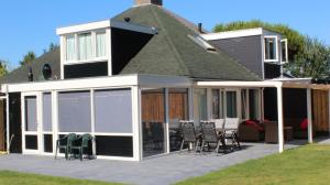 - une extension d'une maison avec des chaises et une terrasse dans l'établissement Nettes Ferienhaus in Stavenisse mit Terrasse und Grill, à Stavenisse