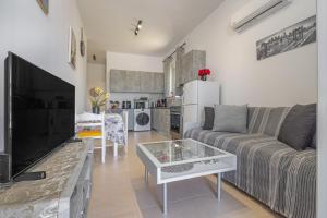 a living room with a couch and a tv at Rania's House Faliraki in Faliraki