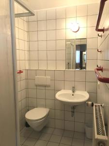 a white tiled bathroom with a toilet and a sink at Ferienhaus in Zandt mit Garten, Terrasse und Grill in Zandt