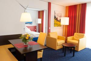 a room with yellow chairs and a table and a bed at Stay2Munich Hotel & Serviced Apartments in Brunnthal