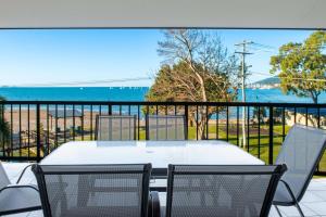 a table and chairs on a balcony with the ocean at Whitsunday Beachfront Apartment on Coral Esplanade in Cannonvale