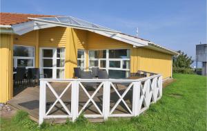 a yellow house with a deck with chairs on it at Strandblick 11 in Schönhagen