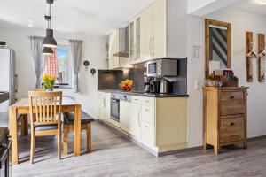 a kitchen with white cabinets and a table with a dining room at Komplett umzäuntes Ferienhaus Plauer See mit Hund in Zislow