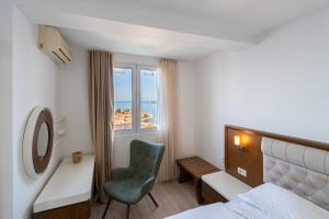 a bedroom with a bed and a chair and a window at Hotel Adrović in Sveti Stefan