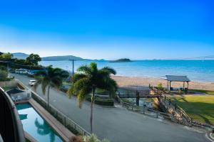 a view of a beach with palm trees and a road at Whitsunday Beachfront Apartment on Coral Esplanade in Cannonvale