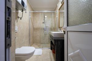 a bathroom with a shower and a toilet and a sink at Hotel Adrović in Sveti Stefan