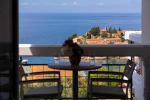a table on a balcony with a view of the ocean at Hotel Adrović in Sveti Stefan