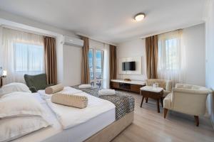 a bedroom with a large bed and a living room at Hotel Adrović in Sveti Stefan
