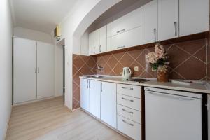 a kitchen with white cabinets and a counter top at Hotel Adrović in Sveti Stefan
