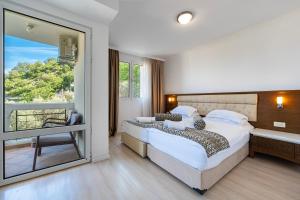 a bedroom with a large bed and a large window at Hotel Adrović in Sveti Stefan