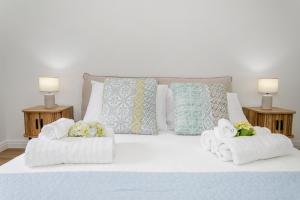 un letto bianco con asciugamani e cuscini sopra di Maria s Haven By The Sea a Ponta Delgada