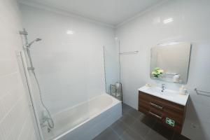 a white bathroom with a tub and a sink at Douro Garden & Rooftop Home in Vila Nova de Gaia +12 photos