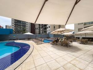una piscina con mesas, sillas y sombrillas en ATRIUM THERMAS Residence Service, en Caldas Novas
