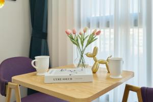 a table with a book and flowers and two cups at Seoul COMOCASA Fully Furnished Studio in Seoul