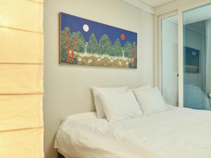 a bedroom with a white bed and a painting on the wall at Seoul COMOCASA Fully Furnished Studio in Seoul +26 photos