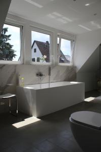a white bathroom with a tub and two windows at Ferienhaus für 6 Personen ca 126 m in Alsbach, Rhein Mittelrheintal in Alsbach