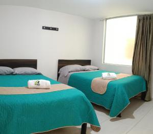 a room with two beds with green sheets and a window at Hotel Riviera Home in Pasto