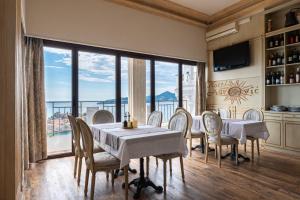 a dining room with tables and chairs and a large window at Hotel Adrović in Sveti Stefan