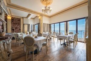 a restaurant with tables and chairs and large windows at Hotel Adrović in Sveti Stefan