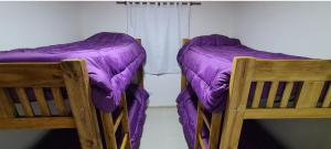 two beds in a room with purple comforter at Departamentos Los Abuelos in General Acha