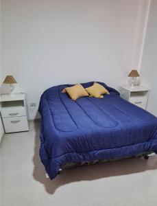 a bed with a blue comforter in a bedroom at Departamentos Los Abuelos in General Acha