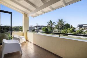 a balcony with white chairs and a view of the city at Villa Sangiovese - Unit Two - 2-2 Heath Street in Evans Head