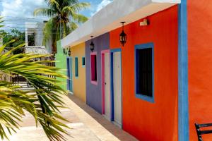 a colorful building with colorful doors and a palm tree at Departamentos privados In Wotoch in Valladolid