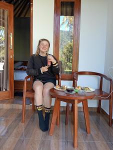 a woman sitting on a chair with a drink at Jepun Homestay Lemukih in Singaraja +23 photos