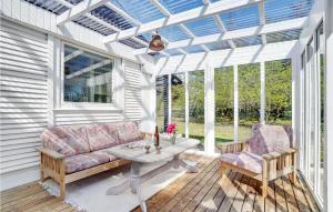 a conservatory with a couch and a table and chairs at Holiday Home Sneppevej Rødby Denm in Kramnitse