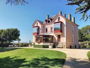 瑞卢维尔莱潘Duplex spacieux à 100m de la plage, 150m des commerces, idéal pour 4 pers, Jullouville - FR-1-361-30的一座大型粉红色房子,前面有草坪