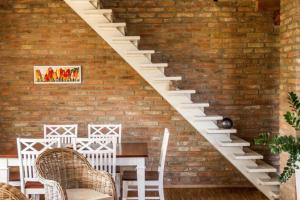 Un escalier blanc dans un mur en briques avec une table et des chaises dans l'établissement Ferienhaus auf zwei Etagen, mit Garten und überdachtem Grillplatz, à Galata