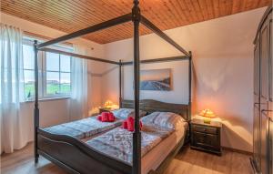 a bedroom with a canopy bed with red pillows on it at Awesome Home In Friedrichskoog-Spitze in Friedrichskoog-Spitz