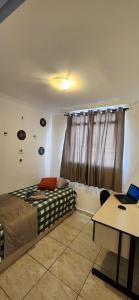a bedroom with a bed and a table with a laptop at AP 3 quartos -2min da ARENA MRV e Expominas- BH in Belo Horizonte