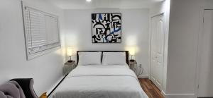 a white bedroom with a bed and two lamps at Room in Halifax - Studio Suite in Halifax