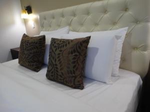 Una cama blanca con dos almohadas encima. en Siena Hotel en Cuenca