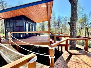 a house with a wooden deck with a tree at Glamping Container Treehouse by Hiawassee Glamping in Hiawassee