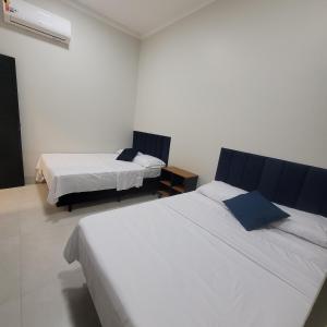 two beds in a room with white walls at Happy Buritis, eventos e hospedagem in Primavera do Leste