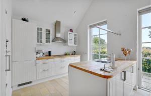 a kitchen with white cabinets and a large window at Three-Bedroom Holiday Home In Krusa in Kruså +15 photos